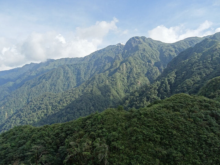 番西邦綠色山稜與山頂建築，雲層在山坡後方
